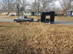 A yard full of leaves and a leaf vacuum truck