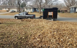 A yard full of leaves and a leaf vacuum truck